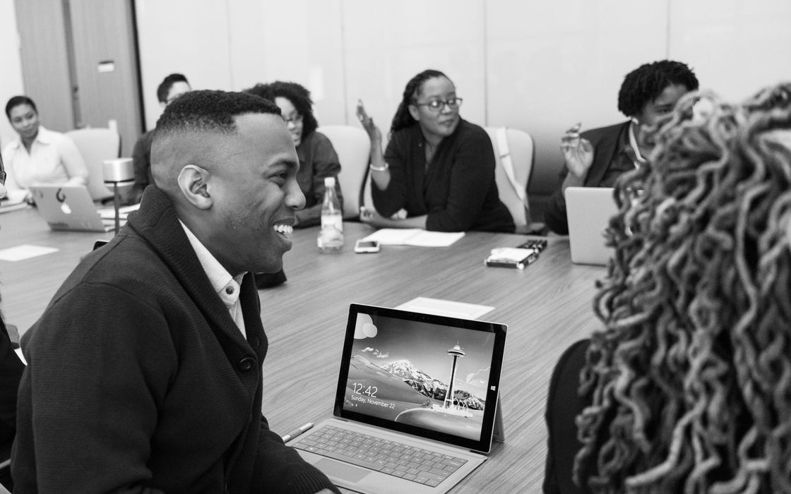 Black leaders gathered around a conference table, laughing in conversation.