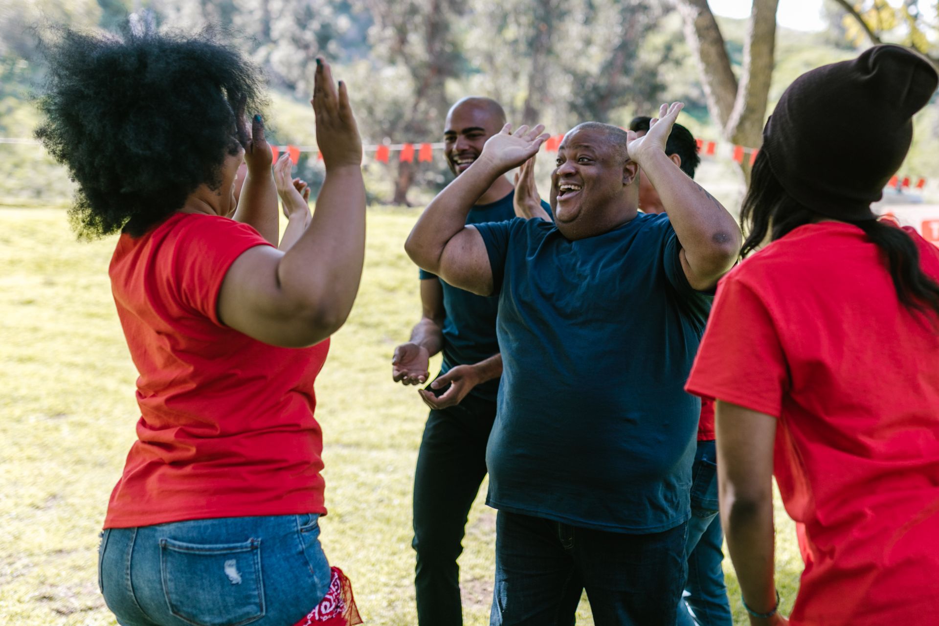 A joyful group of Black friends laughing and high-fiving outdoors