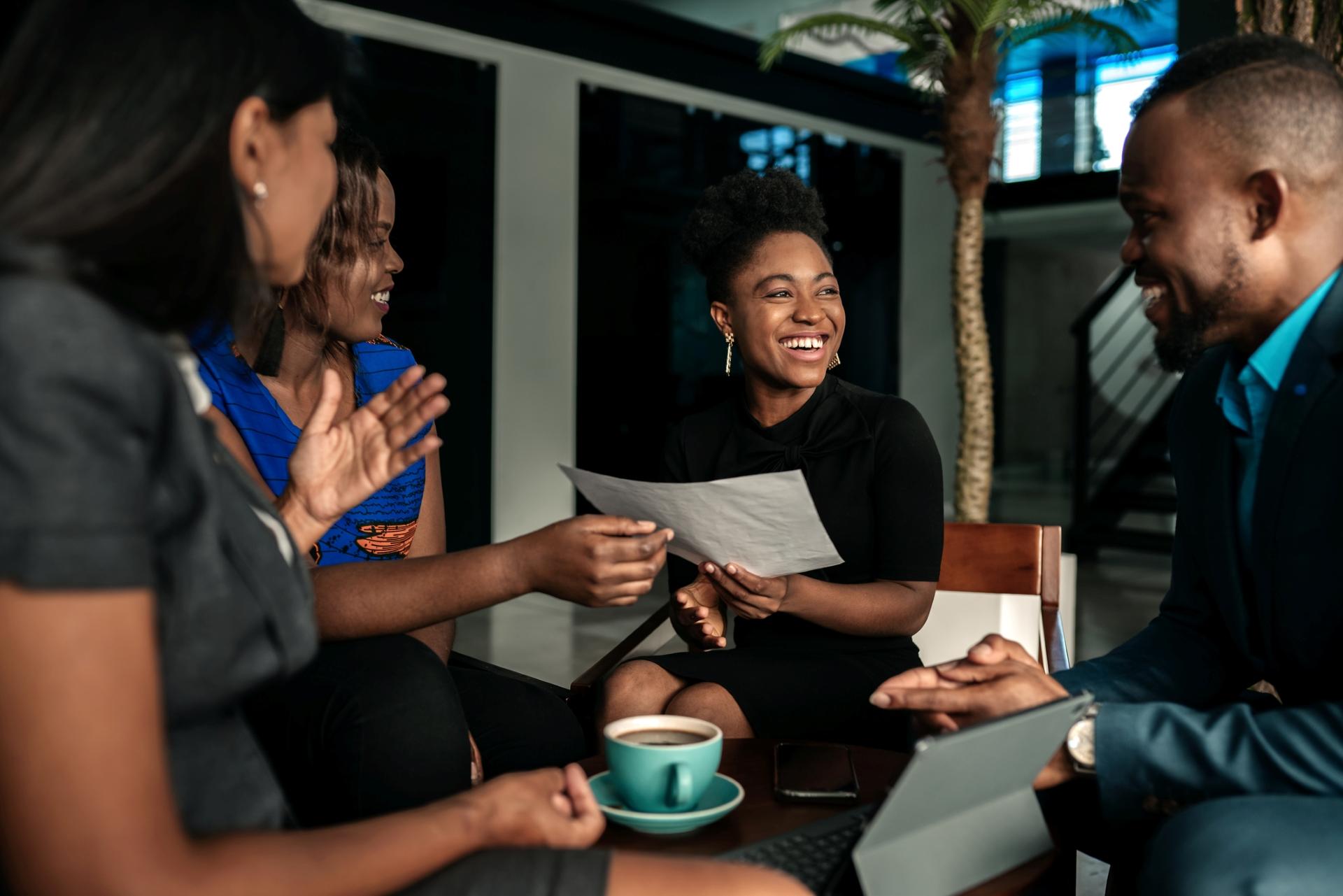 Black leaders in a warm, candid conversation around a table, smiling and exchanging ideas together